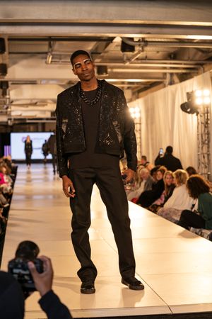 Models walking on a runway showcasing black streetwear fashion in an industrial-style venue.