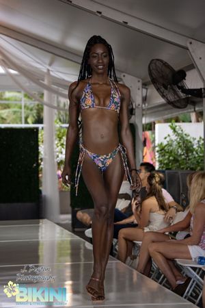 Models present floral print swimwear collection on an outdoor runway with natural lighting.