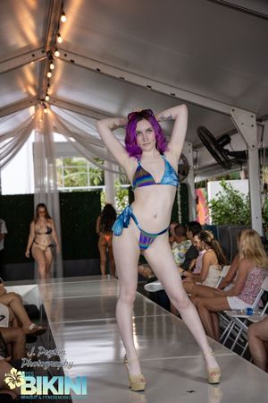 Fashion show featuring colorful bikinis and swimwear with purple and blue designs.