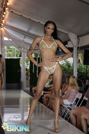 Models showcase animal print swimwear collection on a covered outdoor catwalk.