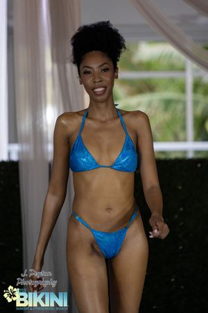 Athletic figure wearing bright blue bikini swimwear poses confidently in indoor setting.