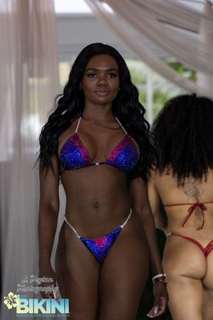 Models present sparkly blue swimwear designs on an illuminated runway.