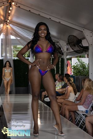 Fashion show featuring purple and blue embellished swimwear designs on the runway.