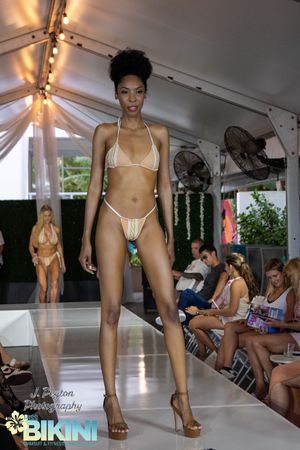 Swimwear models present bikini designs on catwalk during fashion show.