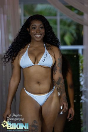 Models walk the runway in white bikinis at a summer fashion show.