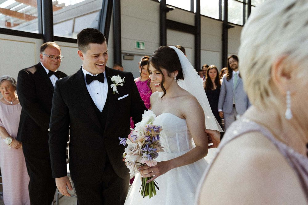 Wedding celebration scene with guests mingling in an elegant indoor venue with natural lighting.