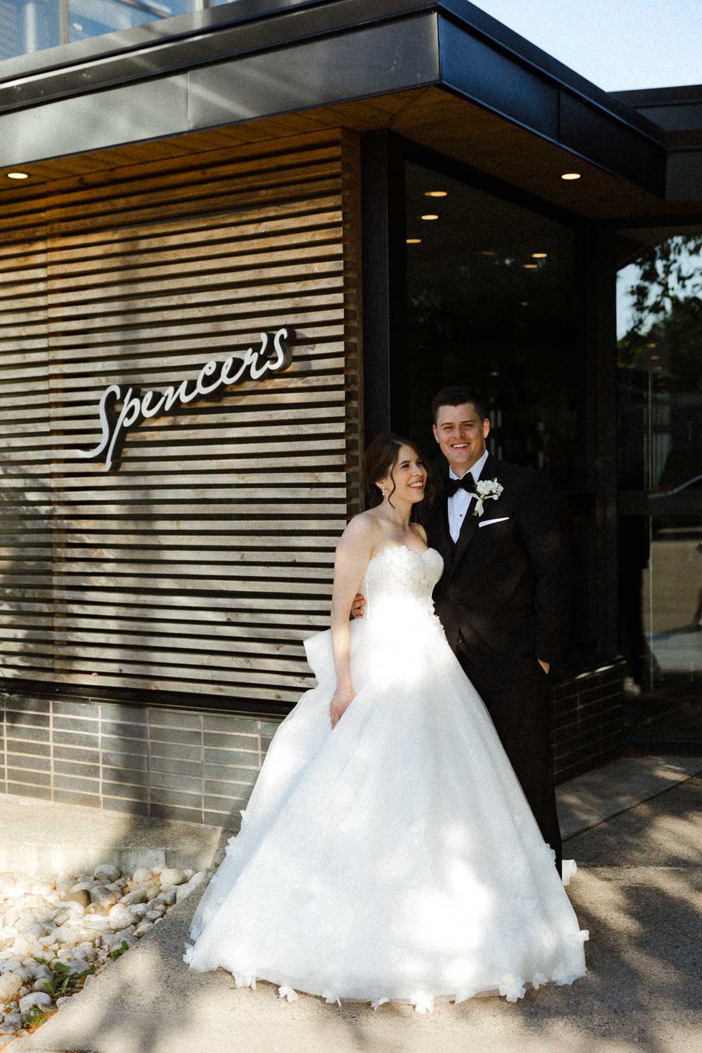 Newlywed couple poses in front of modern building with horizontal slatted exterior design.