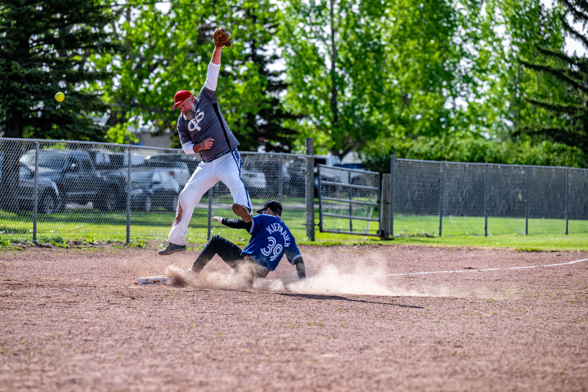 Baseball pitcher in white uniform winds up to throw pitch on dirt mound during game action.