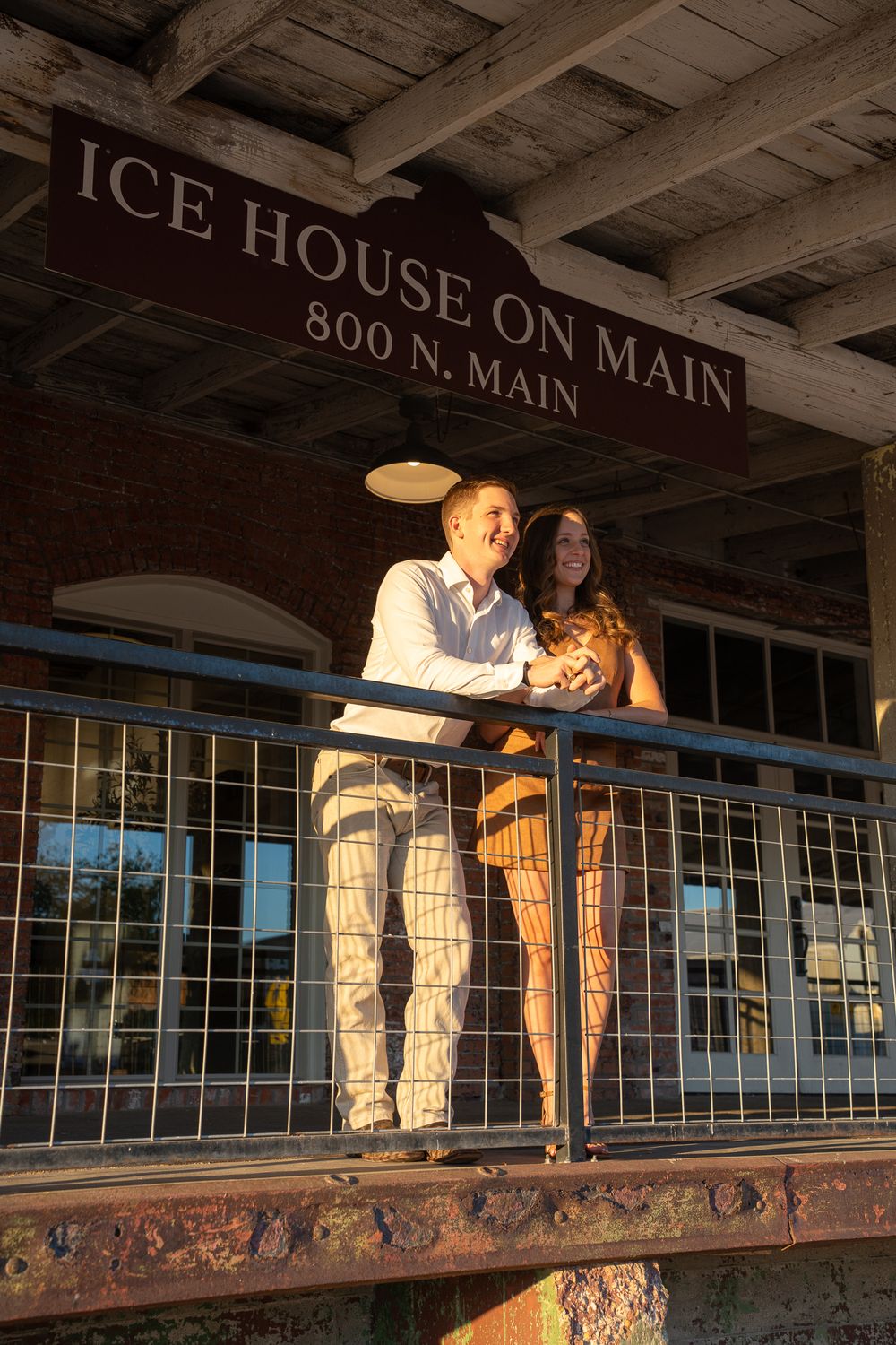 A couple embraces on a rustic balcony at Ice House on Main, an 800 N Main Street building during golden hour.