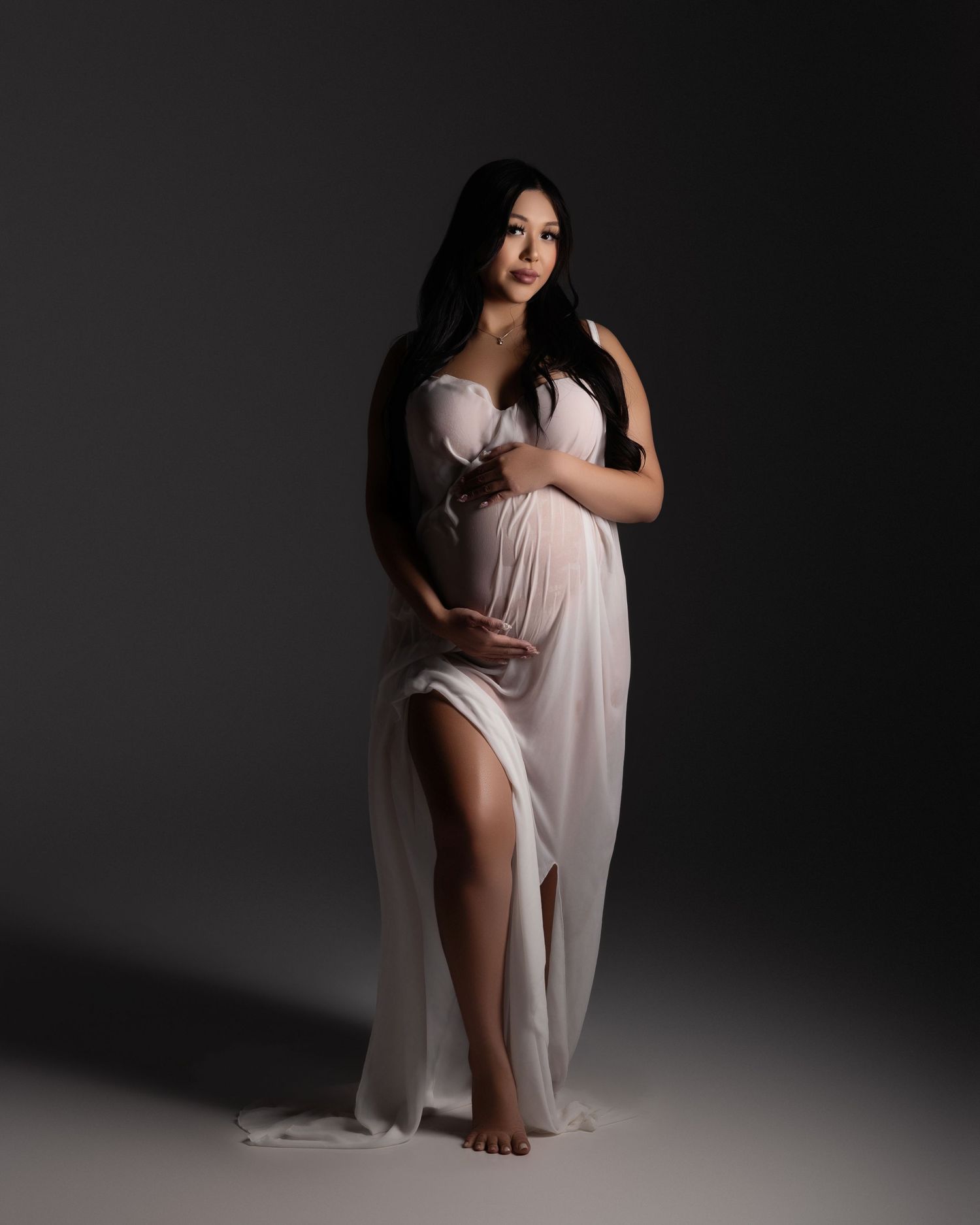 A dramatic studio portrait series in low key lighting shows a figure in a flowing white dress against a dark background.