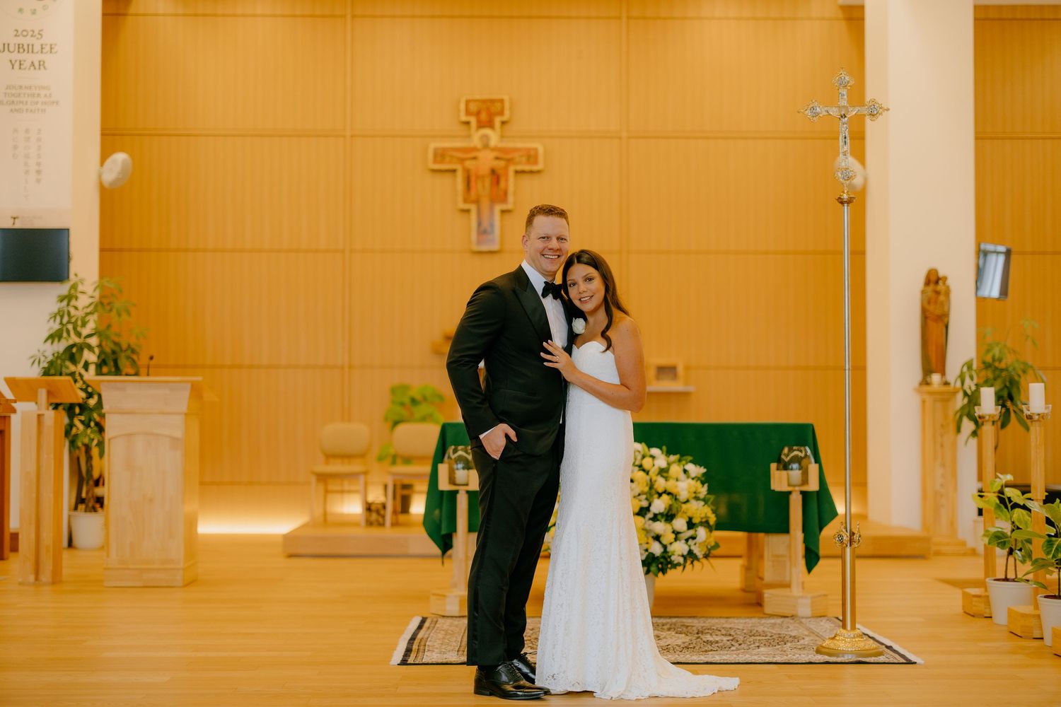 A bride and groom share an intimate moment during their wedding ceremony in a warmly lit church sanctuary.