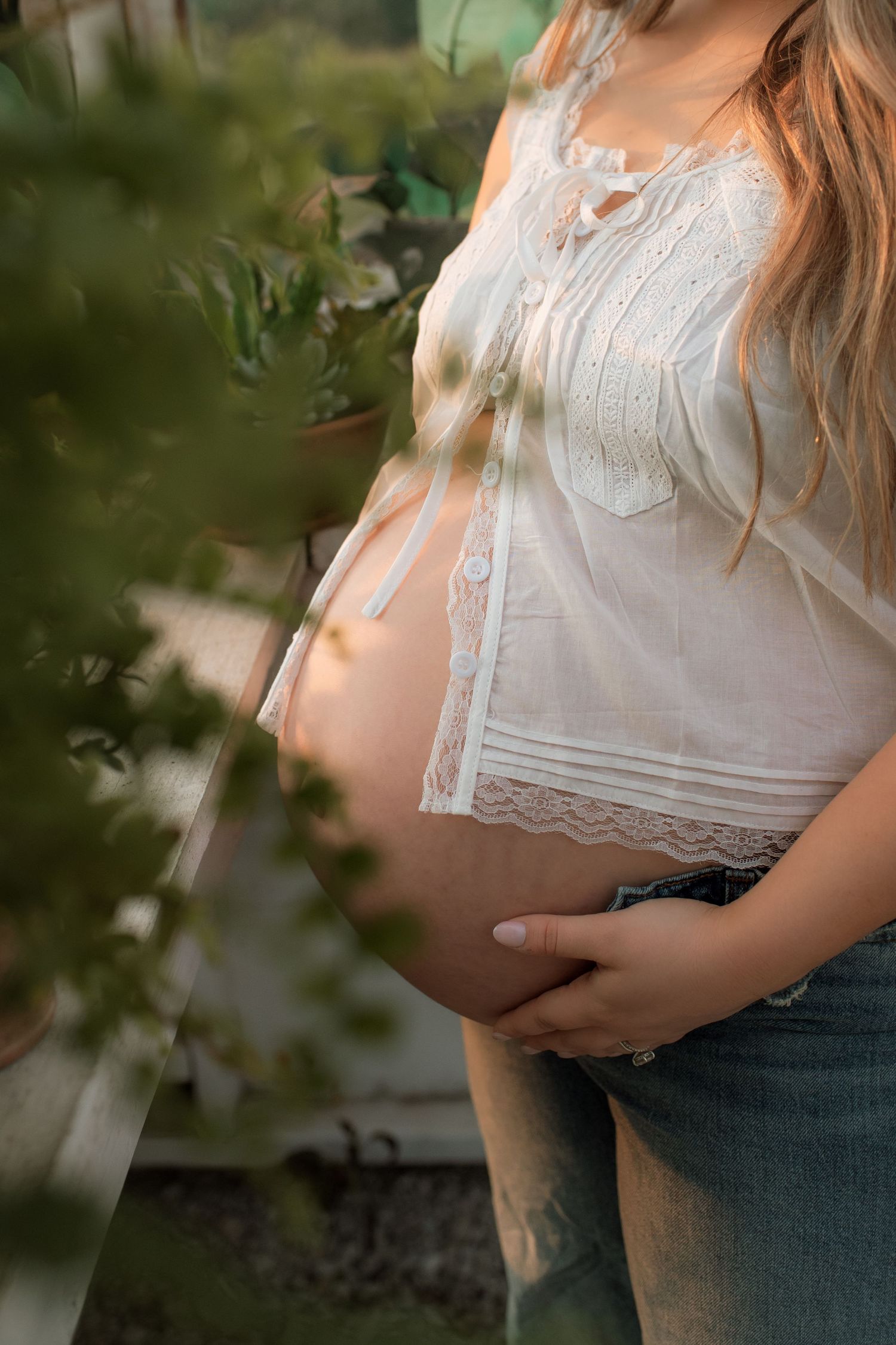 A tender moment between a pregnant woman in a flowing dress and small child standing in a rustic doorway.