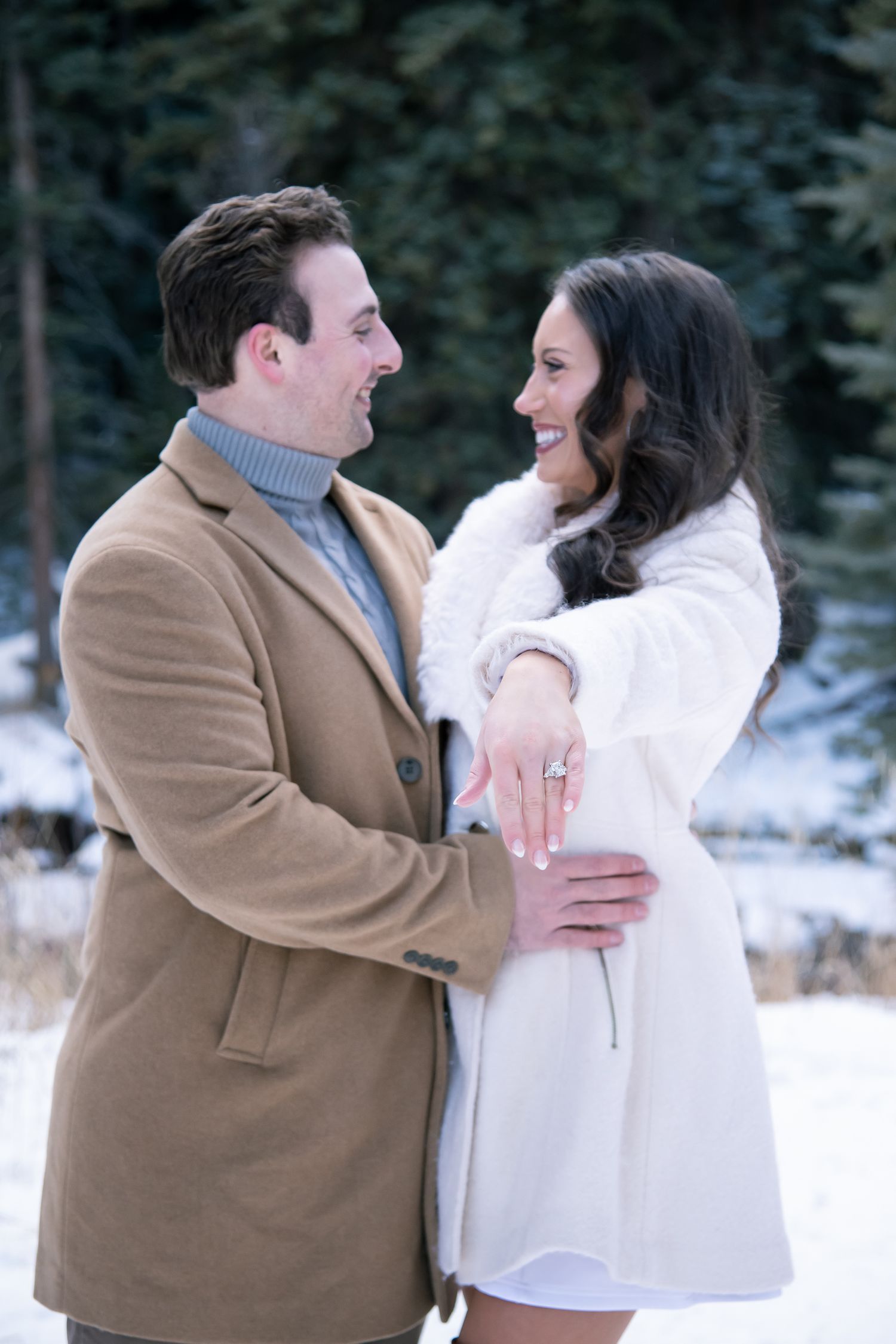 A couple embraces and shows off her new engagement ring after a surprise winter proposal in Vail Colorado