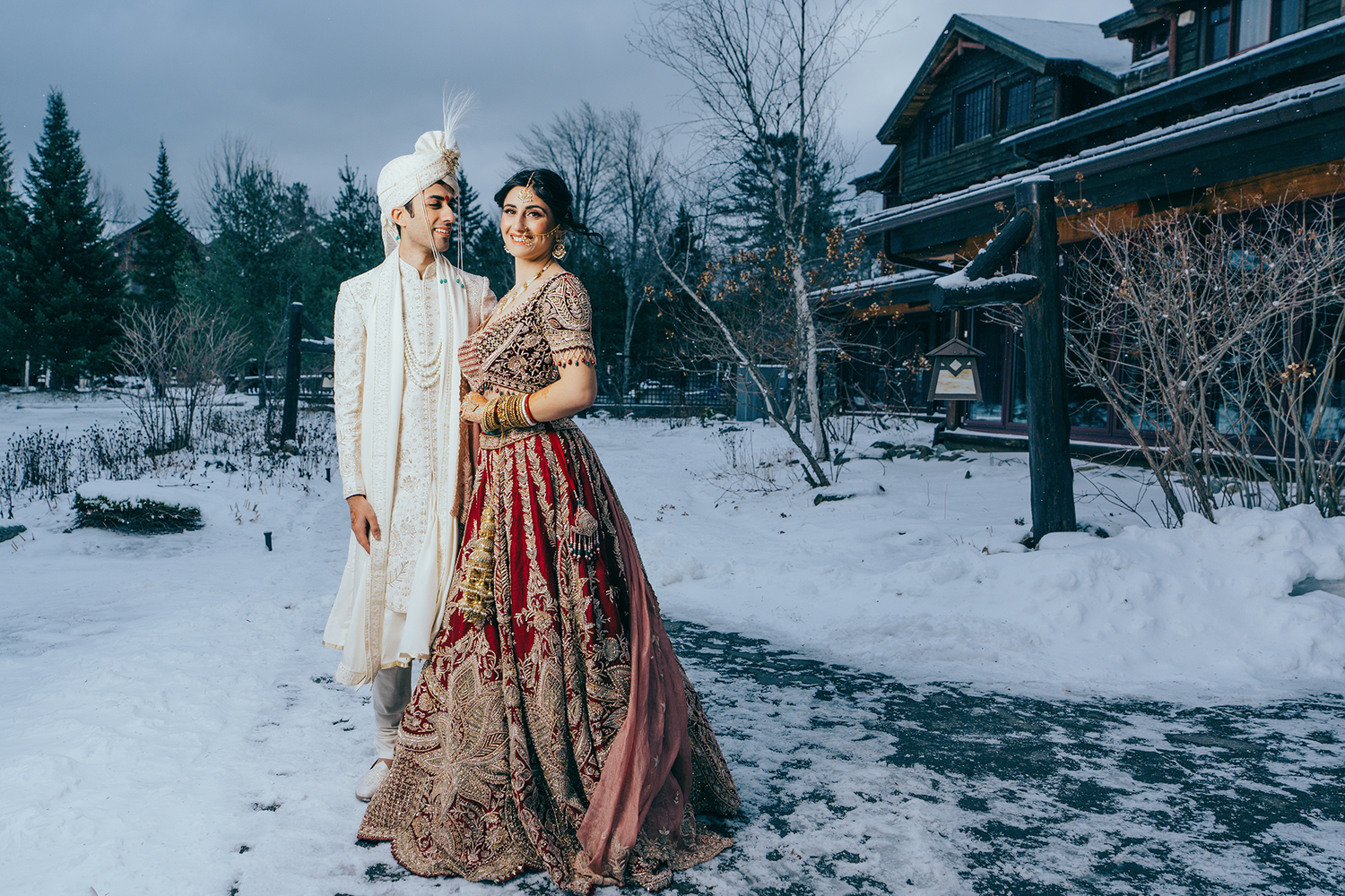 A New York couple in traditional Indian wedding attire poses together in a snowy winter landscape in Lake Placid, NY.