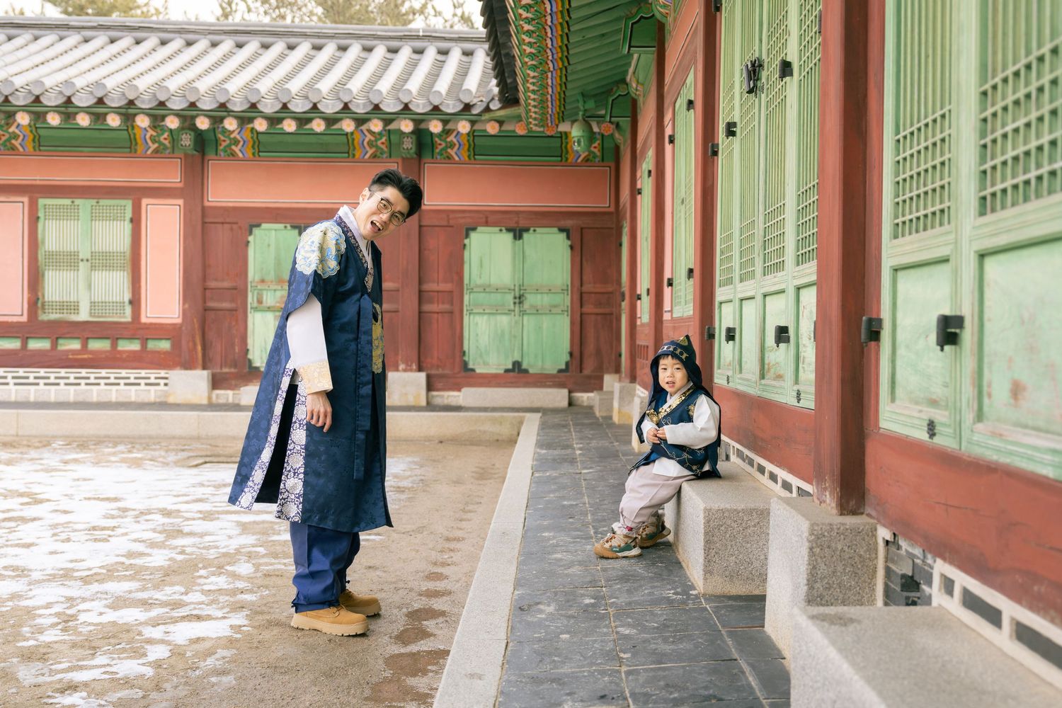 Traditional Korean palace buildings with green painted wooden columns and ornate architectural details line a covered walkway.