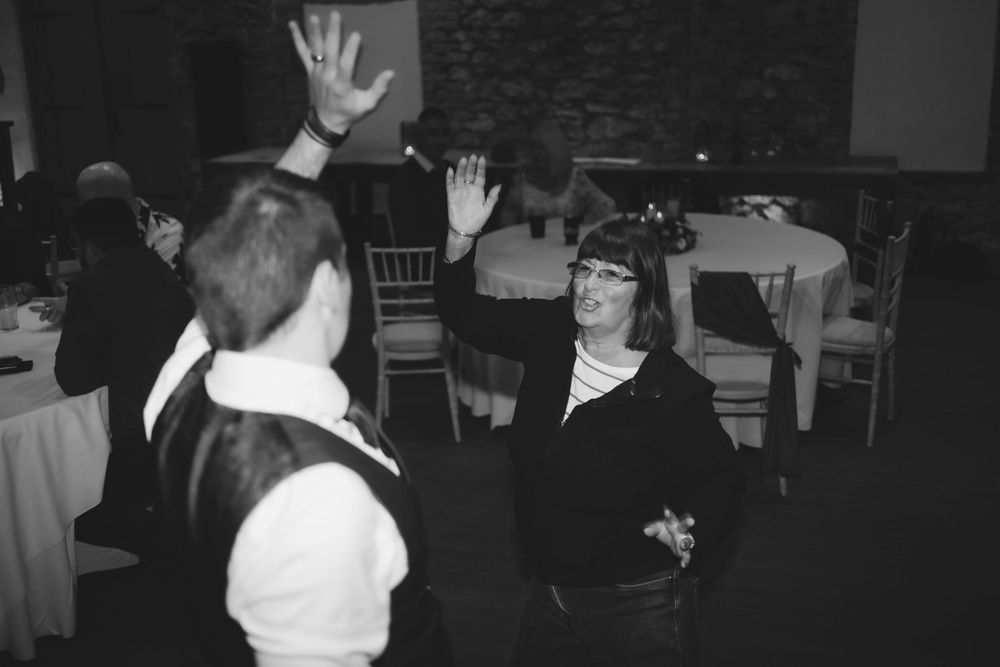 Black and white photo of people dancing at a party with hands raised in celebration.
