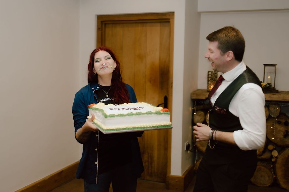 A couple in formal attire cuts their wedding cake together at a reception celebration.