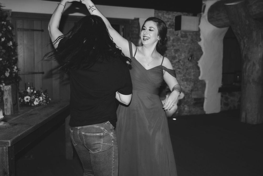 Black and white photo of a couple dancing together in formal attire at what appears to be a wedding reception.