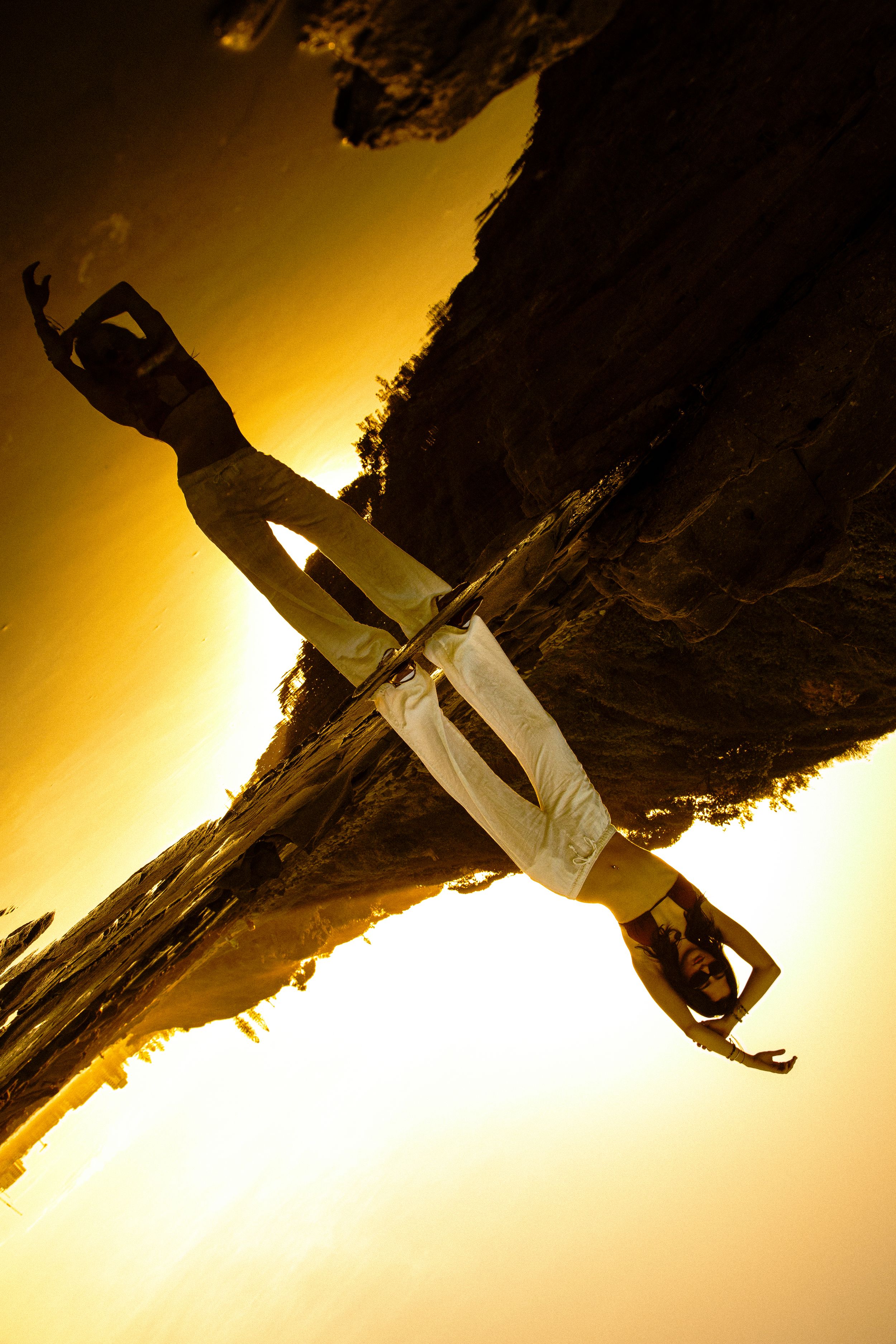 Silhouette against golden sunset sky with dramatic rock formation perspective.
