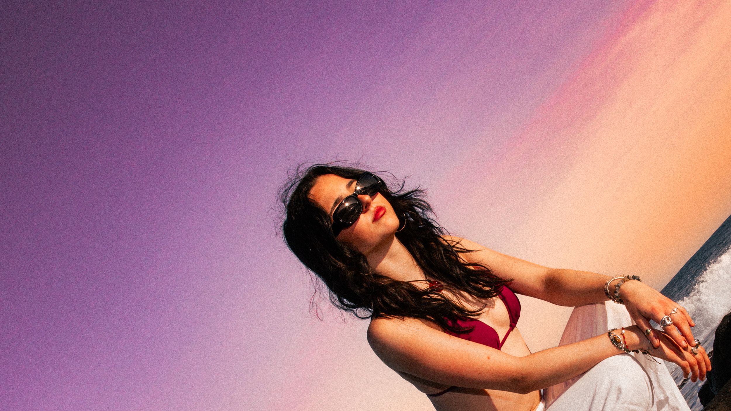Artistic portrait against vibrant purple and orange gradient background.