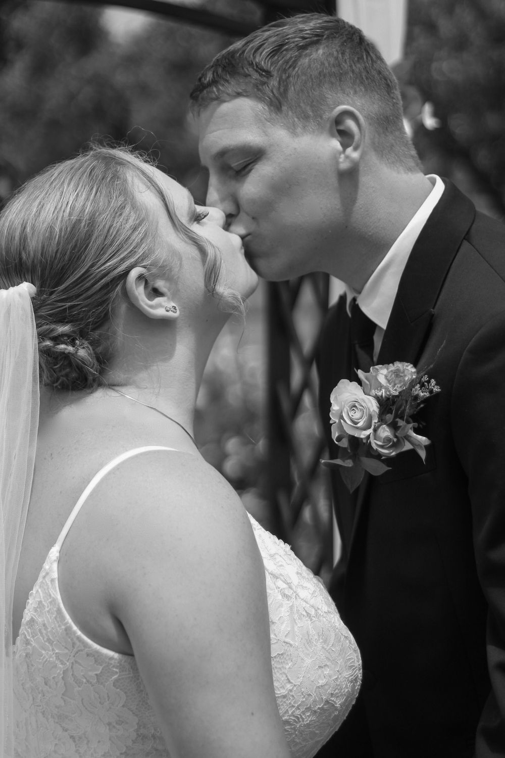 Black and white close-up of bride and groom sharing their first kiss at the altar.