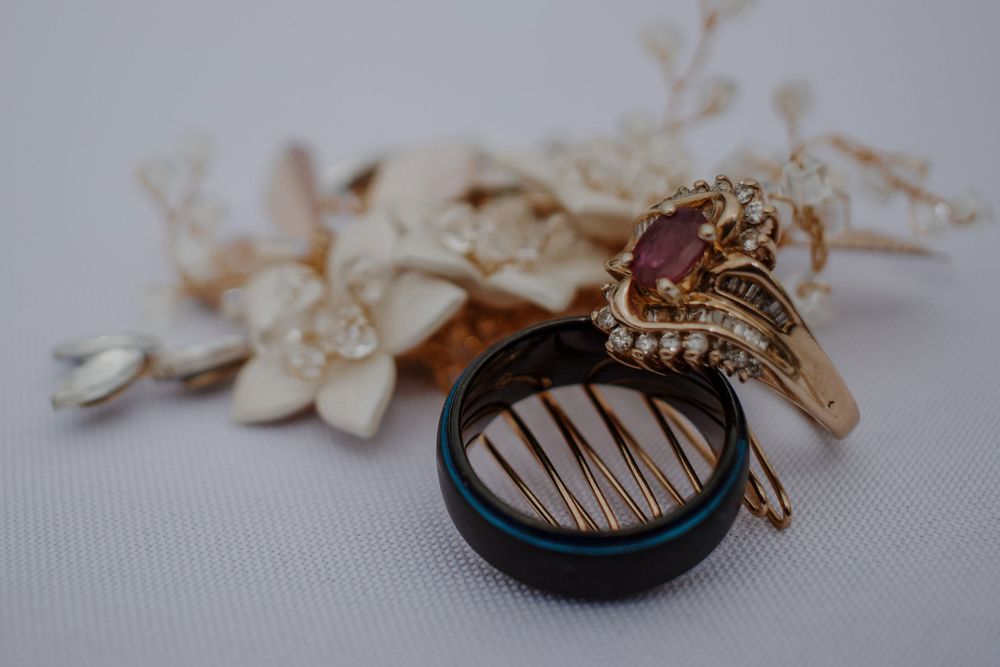 Close-up of elegant gold engagement ring with ruby gemstone and diamond accents resting on decorative hair comb.