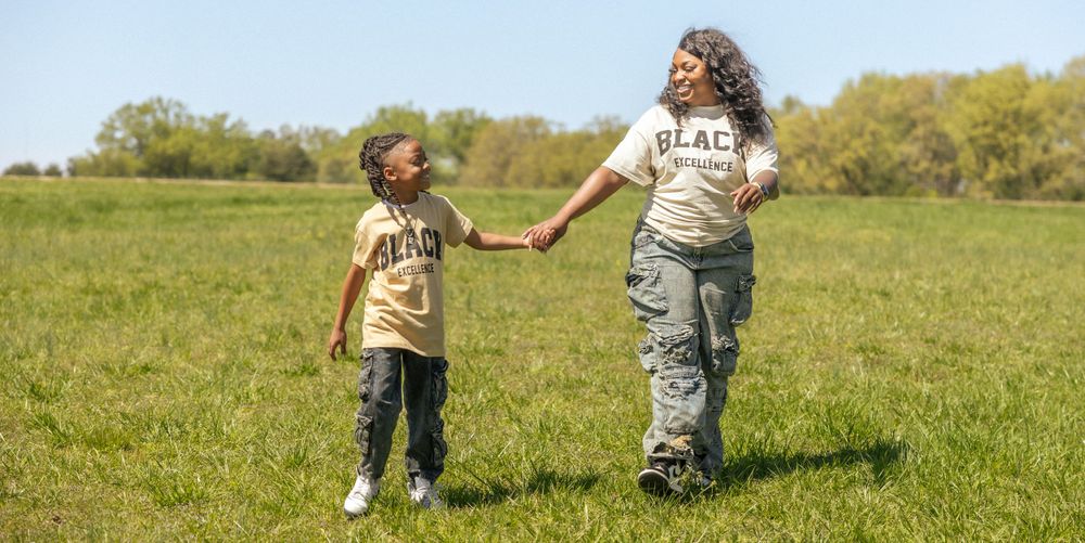 Two people hold hands while walking together across a sunny meadow on a spring day.