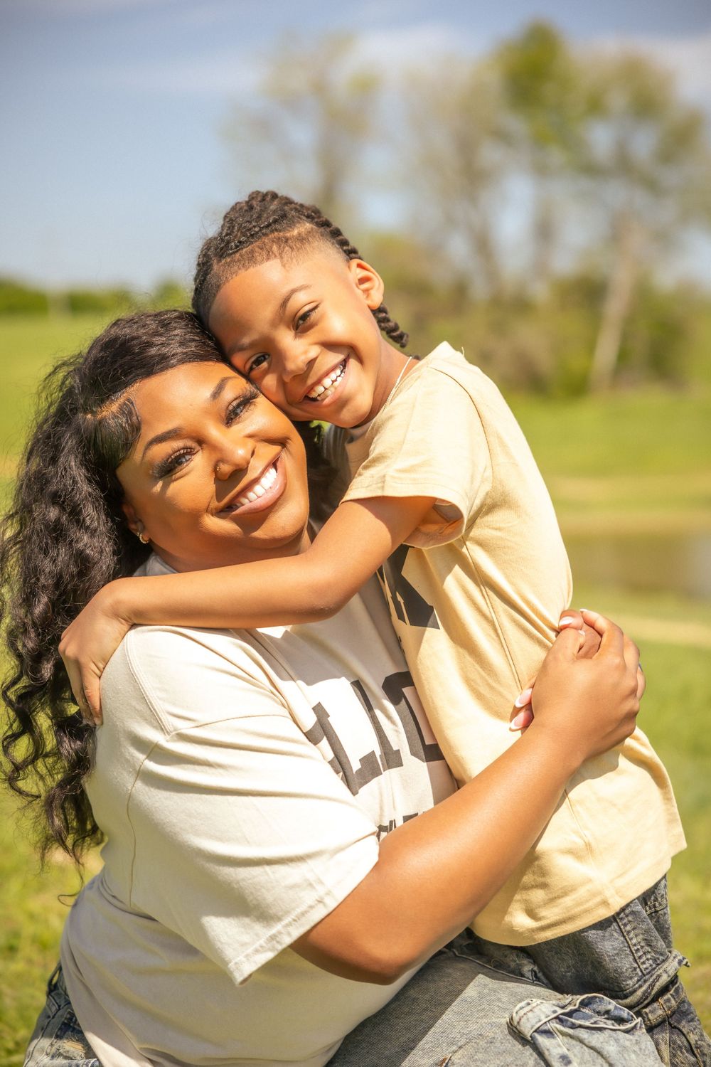 Two people share loving laughter and a warm hug while posing together in a natural outdoor setting.