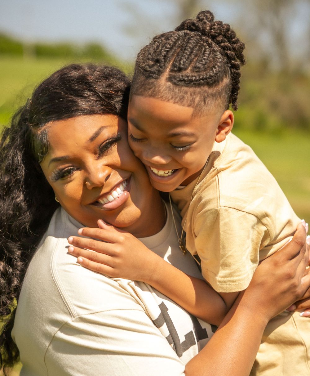A joyful outdoor moment shows warmth and laughter between parent and child on a sunny day.
