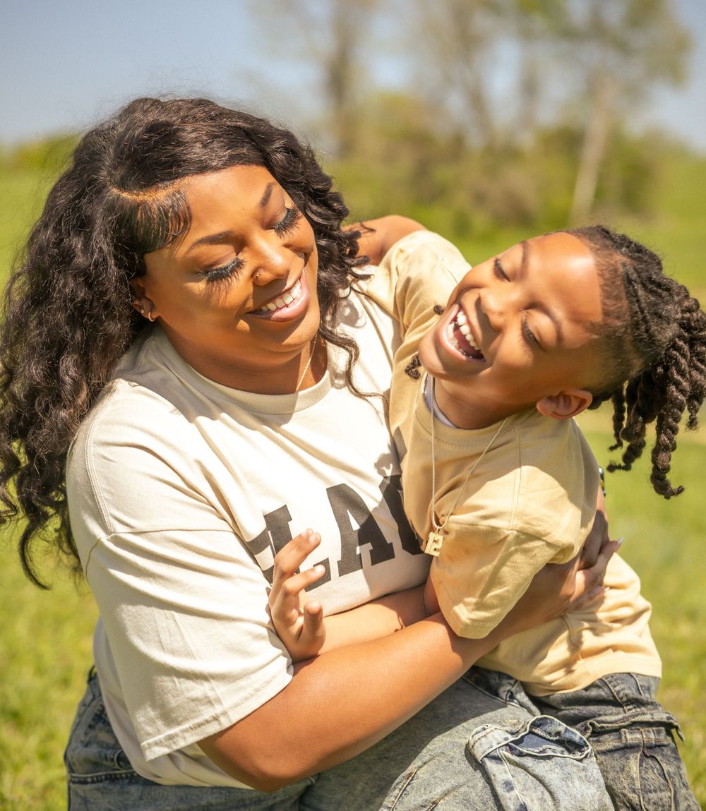 A joyful candid moment shared between parent and child playing together outdoors on a sunny day.
