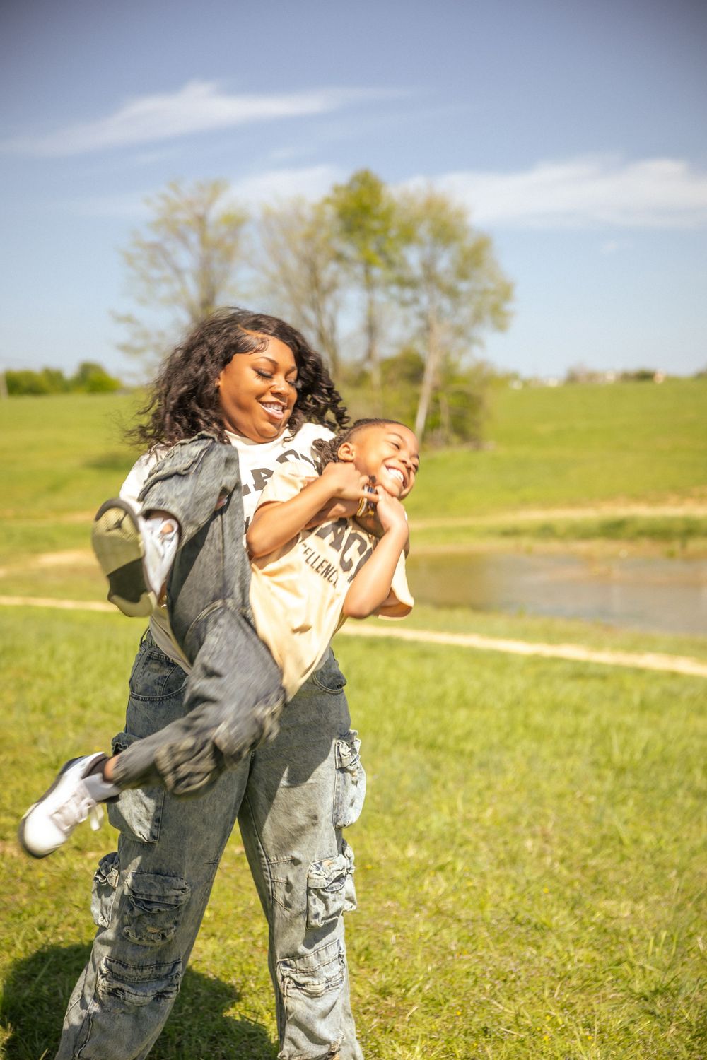 Person playfully swinging their companion in a grassy field on a sunny afternoon.