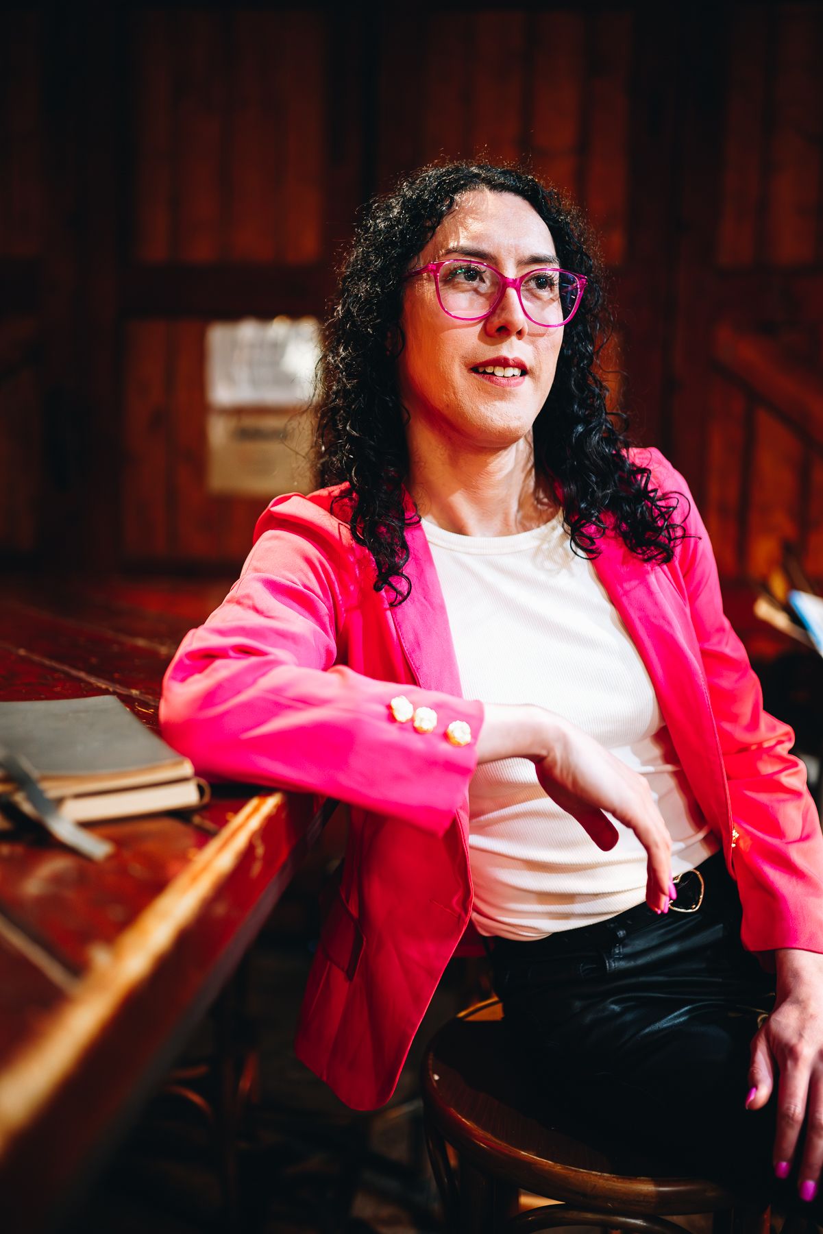 Melbourne branding photo of a professional in pink blazer and glasses, seated in warm, wooden interior—lifestyle photography at its best.
