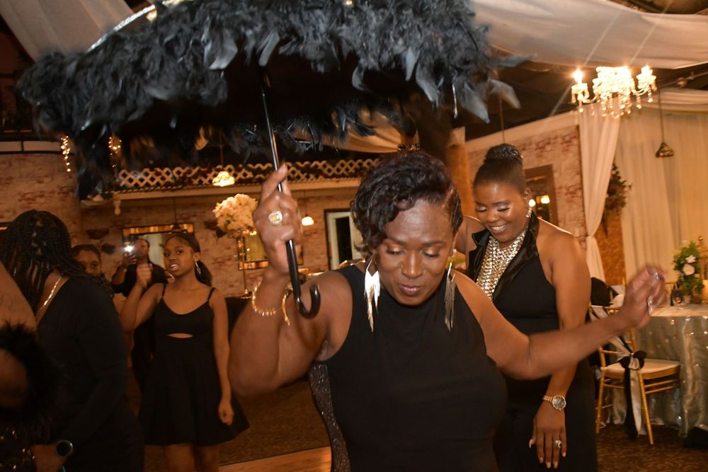 A person dancing under black feather decorations at a formal party venue.