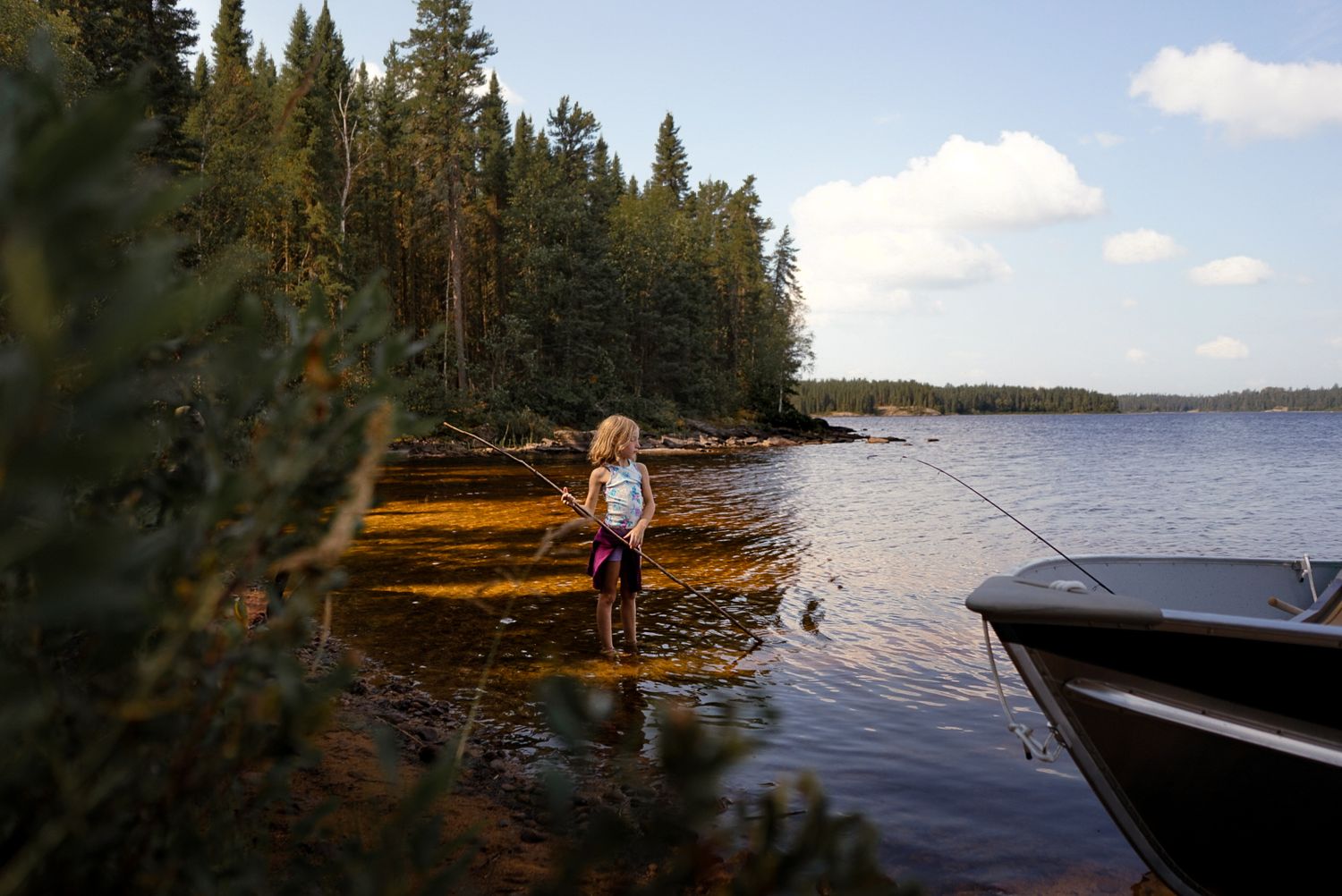 Float plane and boat on pristine wilderness lake surrounded by pine forest.