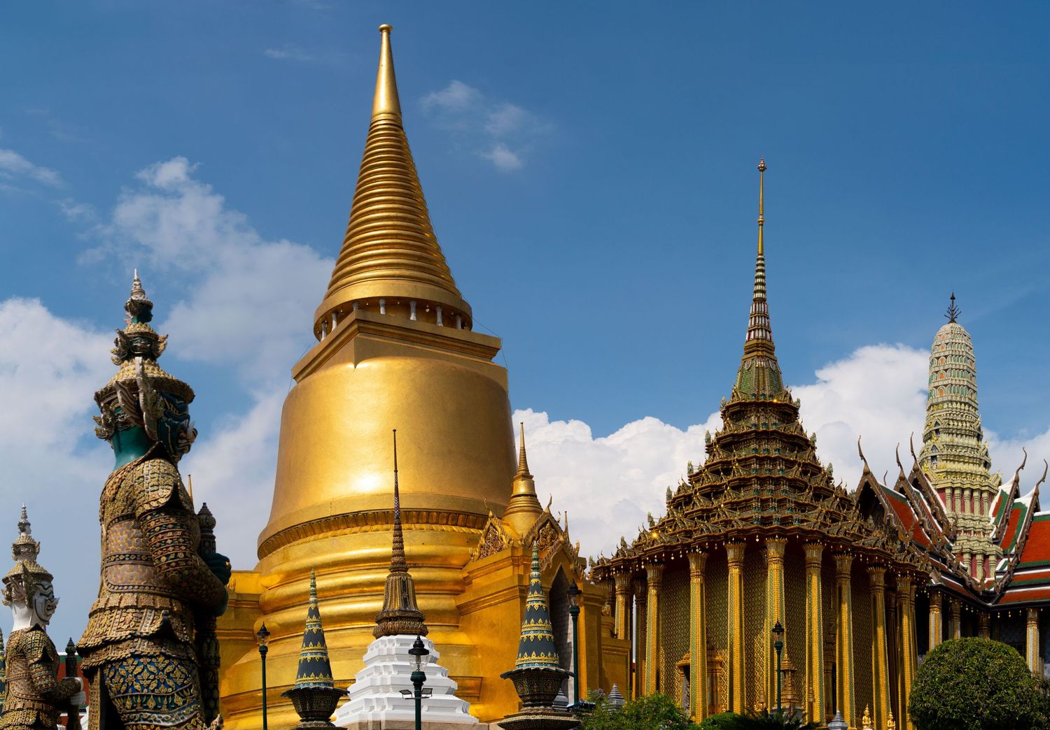 Panoramic view of golden stupas and temple buildings at Bangkok's Grand Palace complex.
