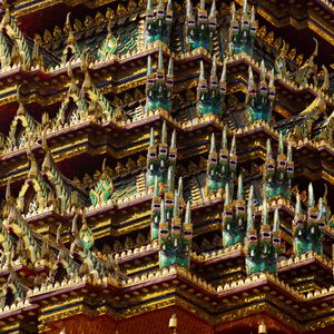 Intricate Thai temple roof decorations with multiple tiers of ornate golden details.