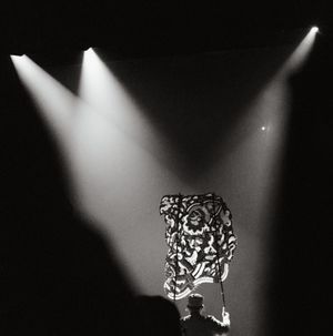 Dramatic spotlight illuminating a traditional Thai performance figure in darkness.