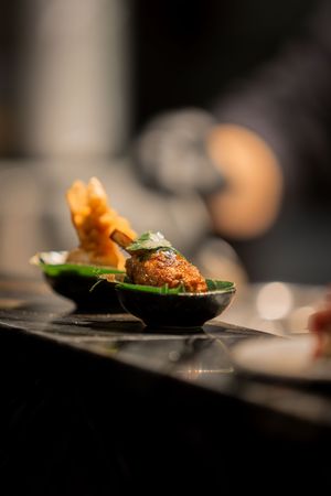 Close-up of an elegantly plated appetizer with tempura on a black dish.
