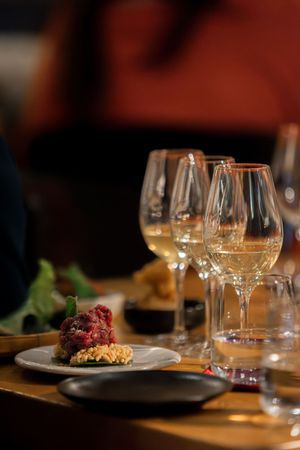 Fine dining table setting with wine glasses and plated dish in warm lighting.