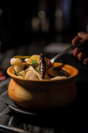Dumplings and vegetables served in rustic ceramic bowl with chopsticks.
