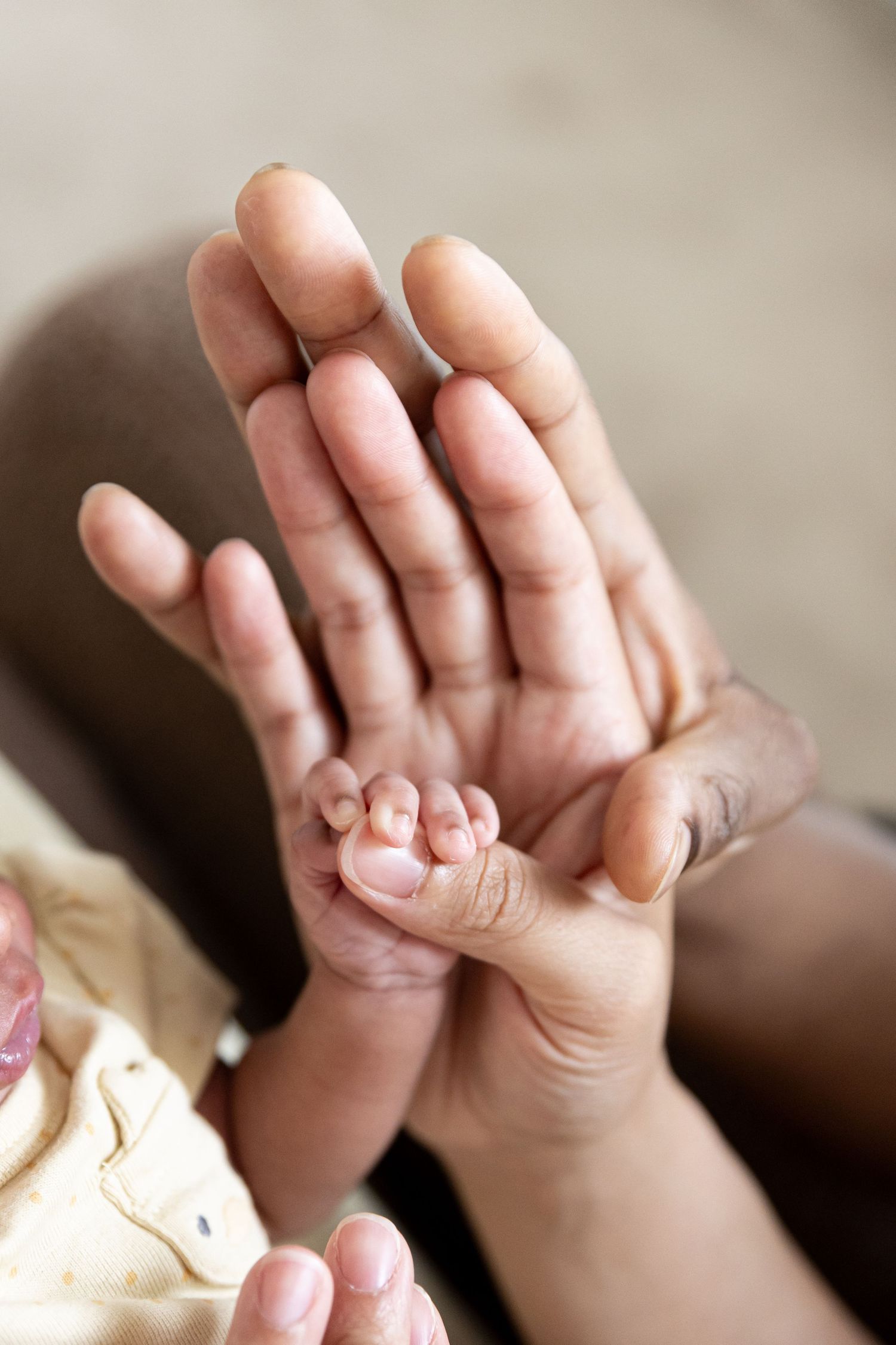 A tiny newborn baby hand gently grasping an adult's open palm, symbolizing love and new life.