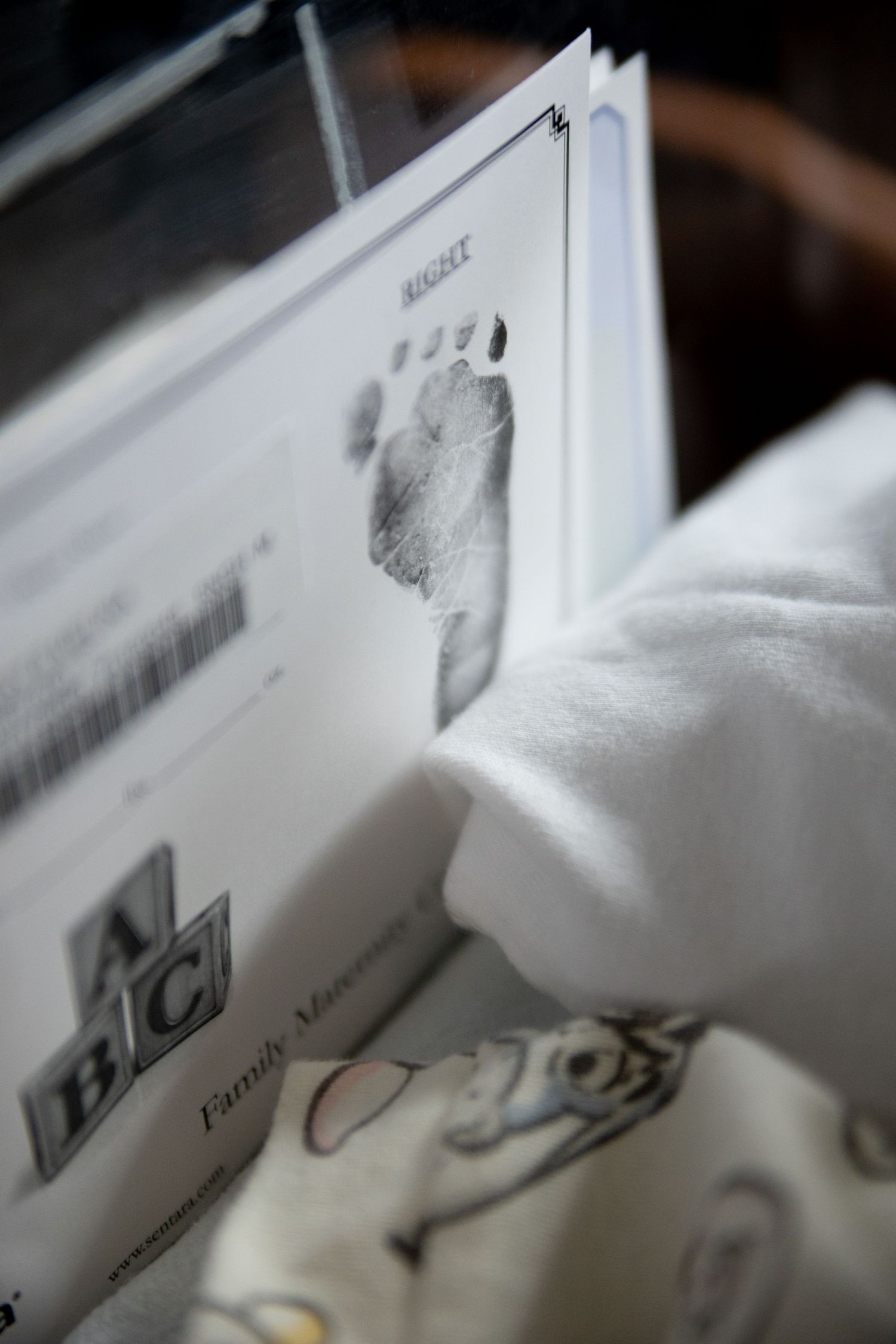 A close-up shot of a baby footprint record in a medical document against white fabric background.