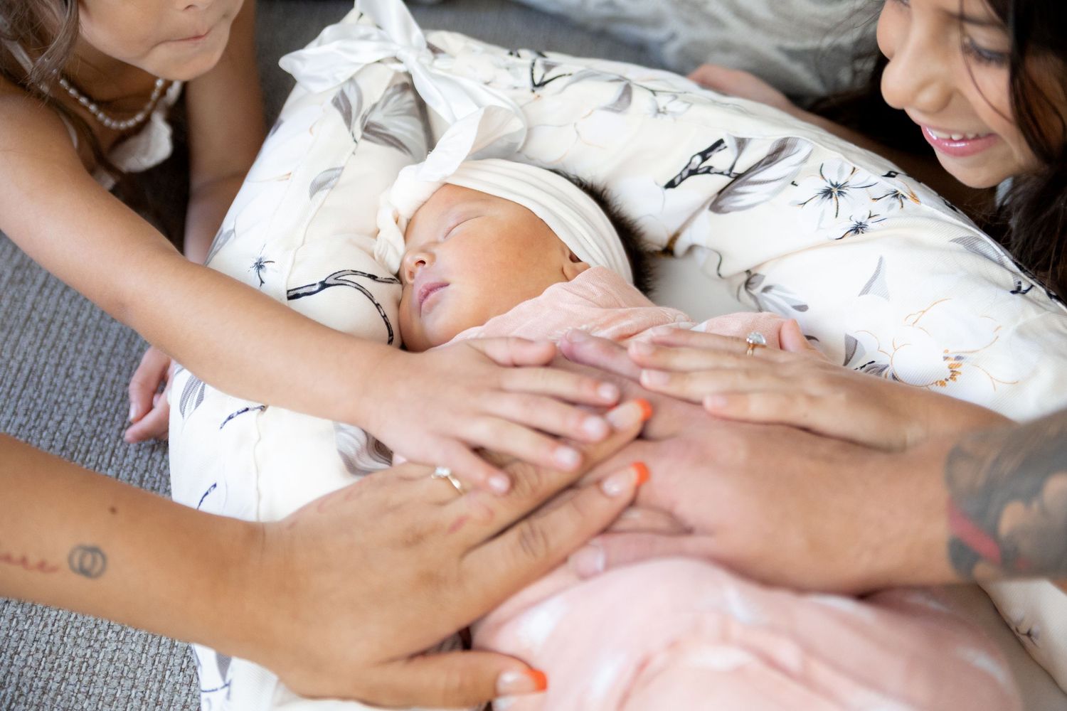 A close-up of hands holding and gently caressing hands in a tender moment against white bedsheets.