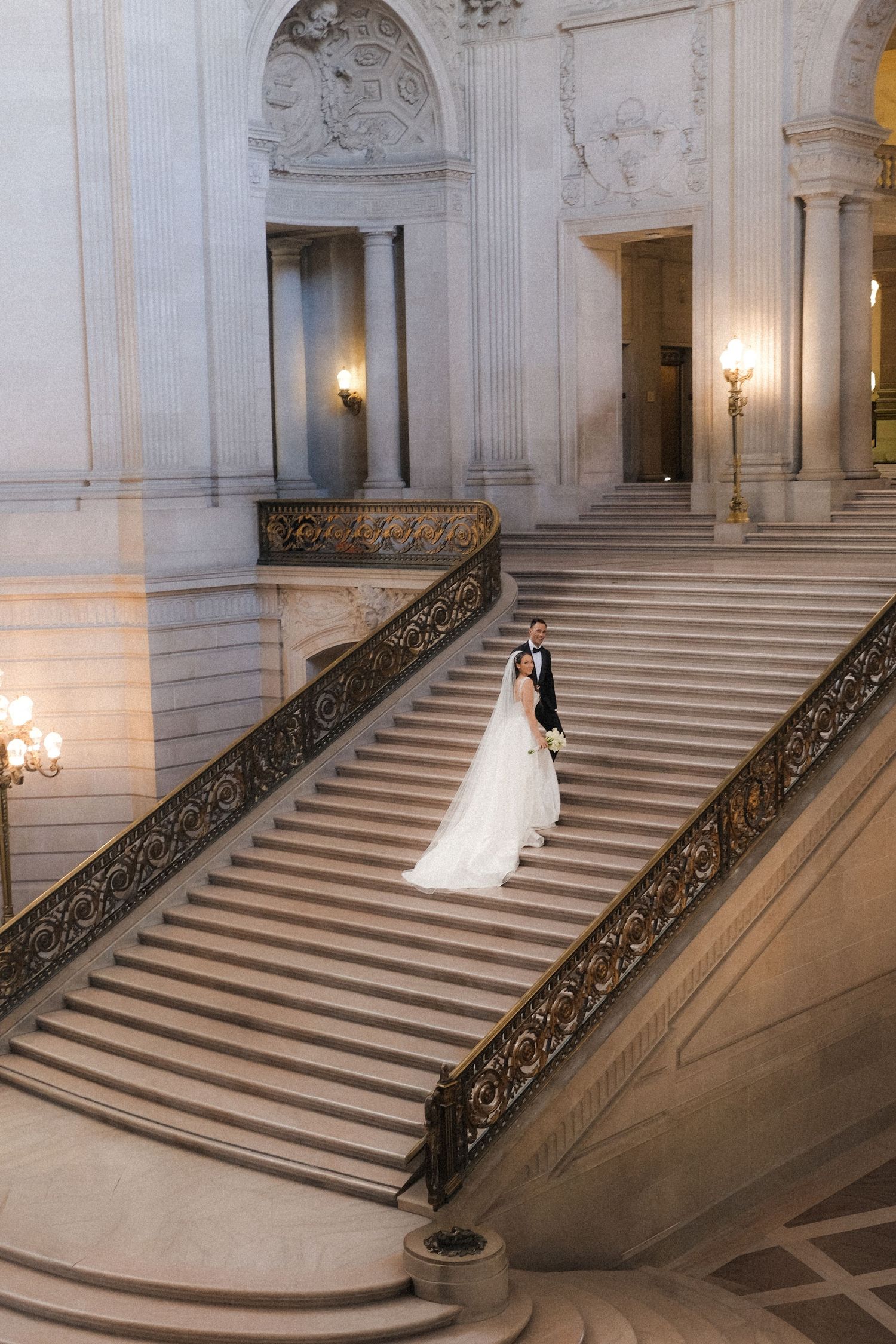 Bride and groom share a romantic moment on the grand staircase of San Francisco City Hall on their wedding day.
