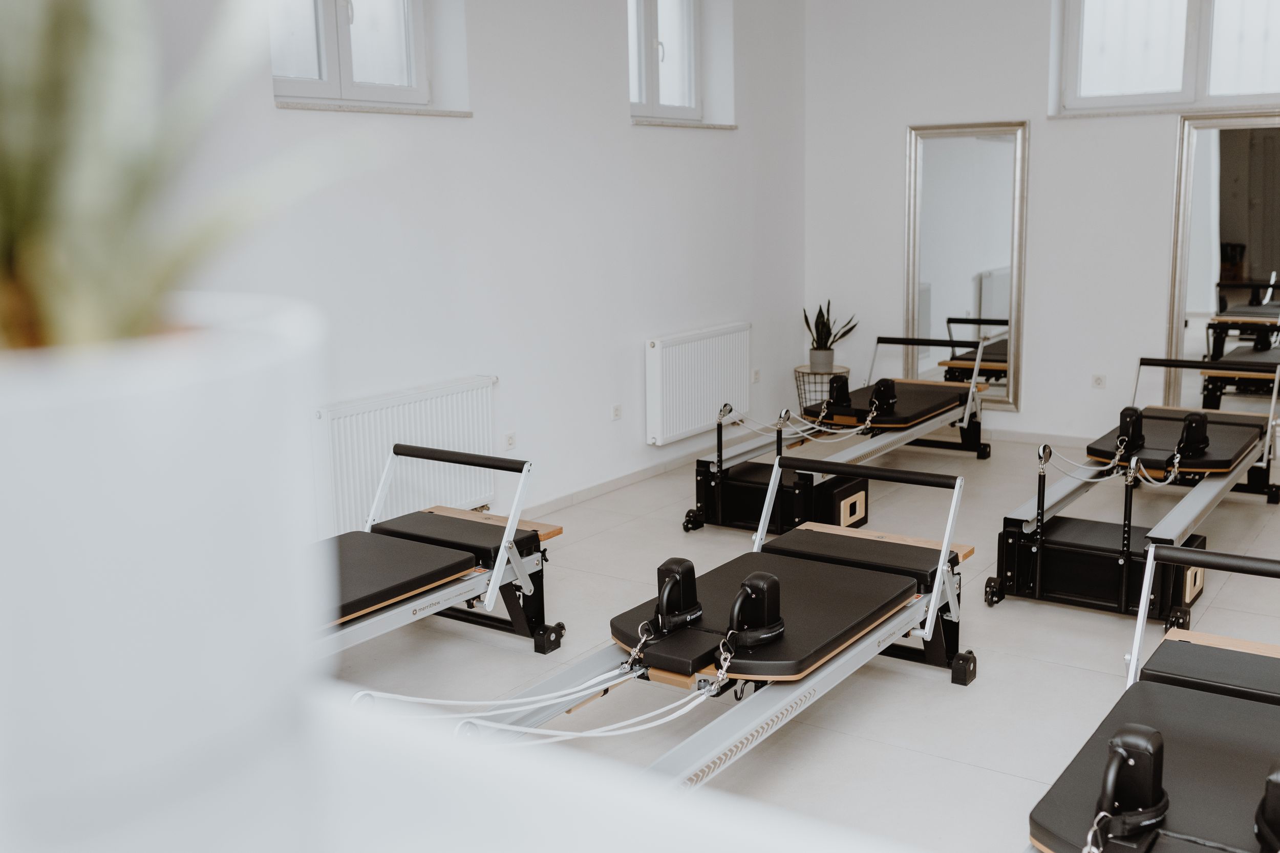 Wide shot of a modern Pilates reformer studio in Zagreb, showcasing brand photography of neatly arranged reformer machin