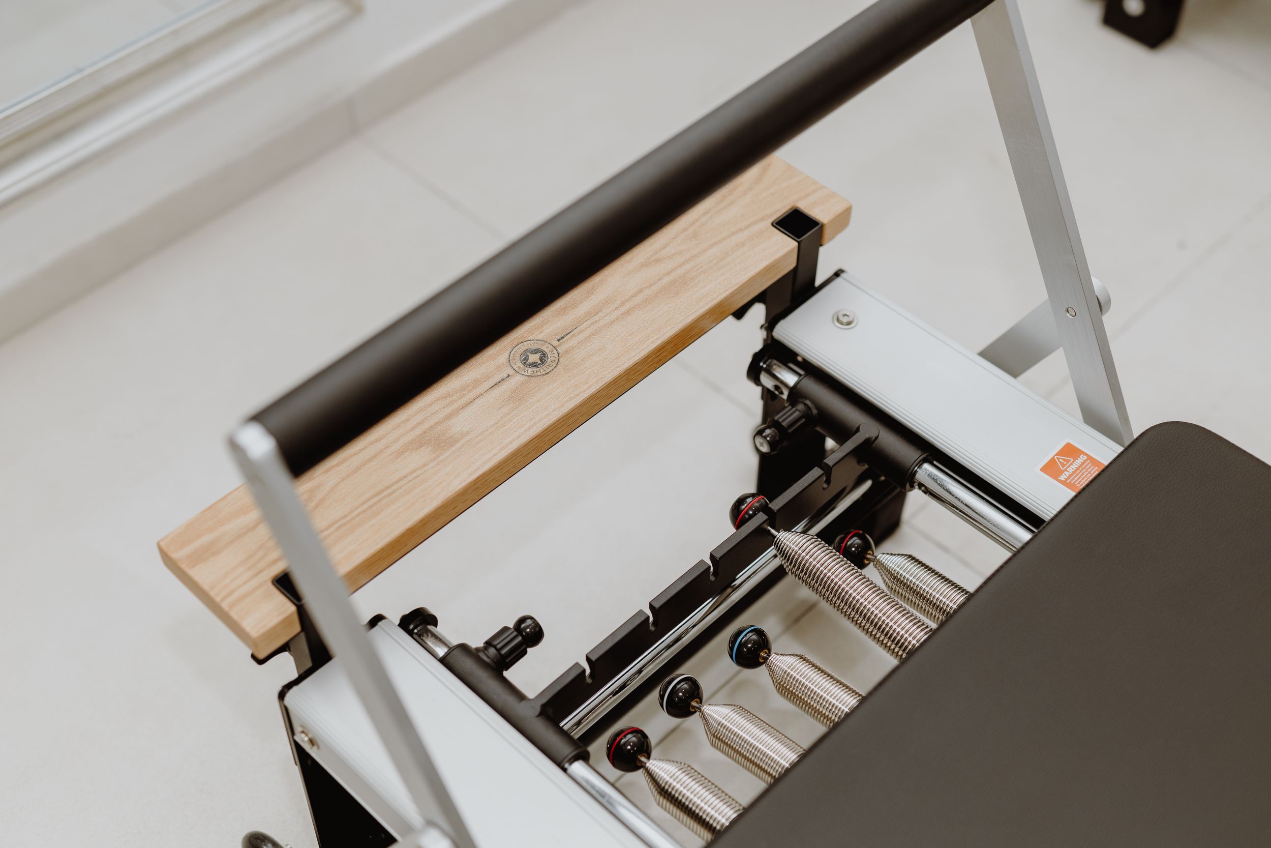 Close up detail of wooden and metal Pilates reformer machine equipment.