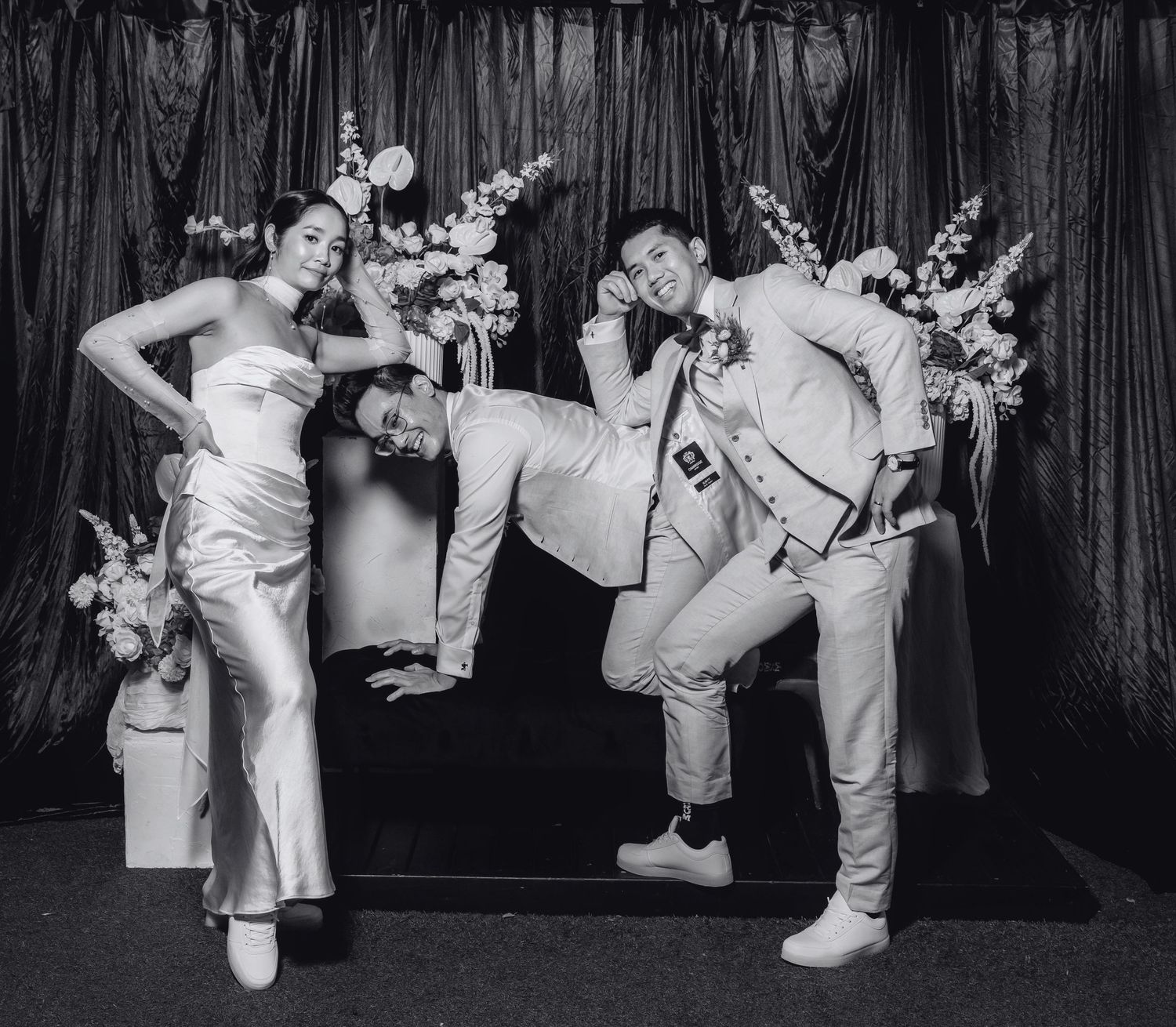 Bride and groom jumping joyfully under disco balls with sparklers in a dark wedding venue.