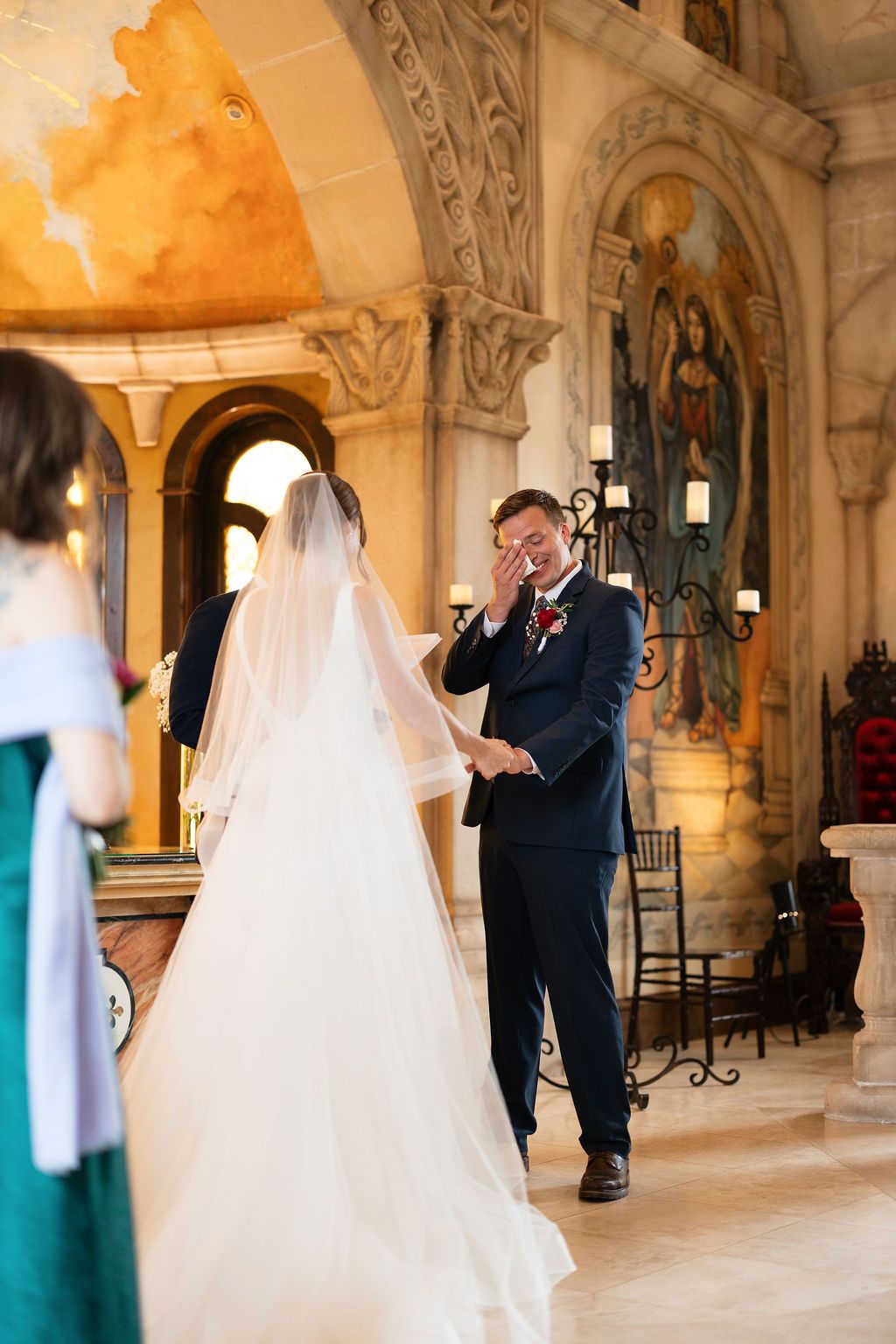 Emotional groom wiping tears as bride walks down the aisle in a stunning church wedding ceremony.
