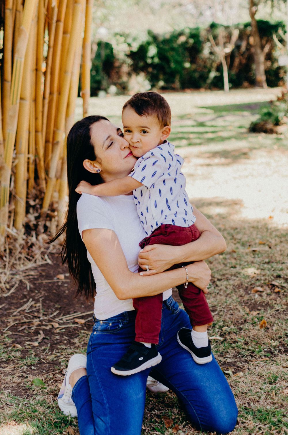 A tender embrace shared in front of bamboo stalks in a natural garden setting.