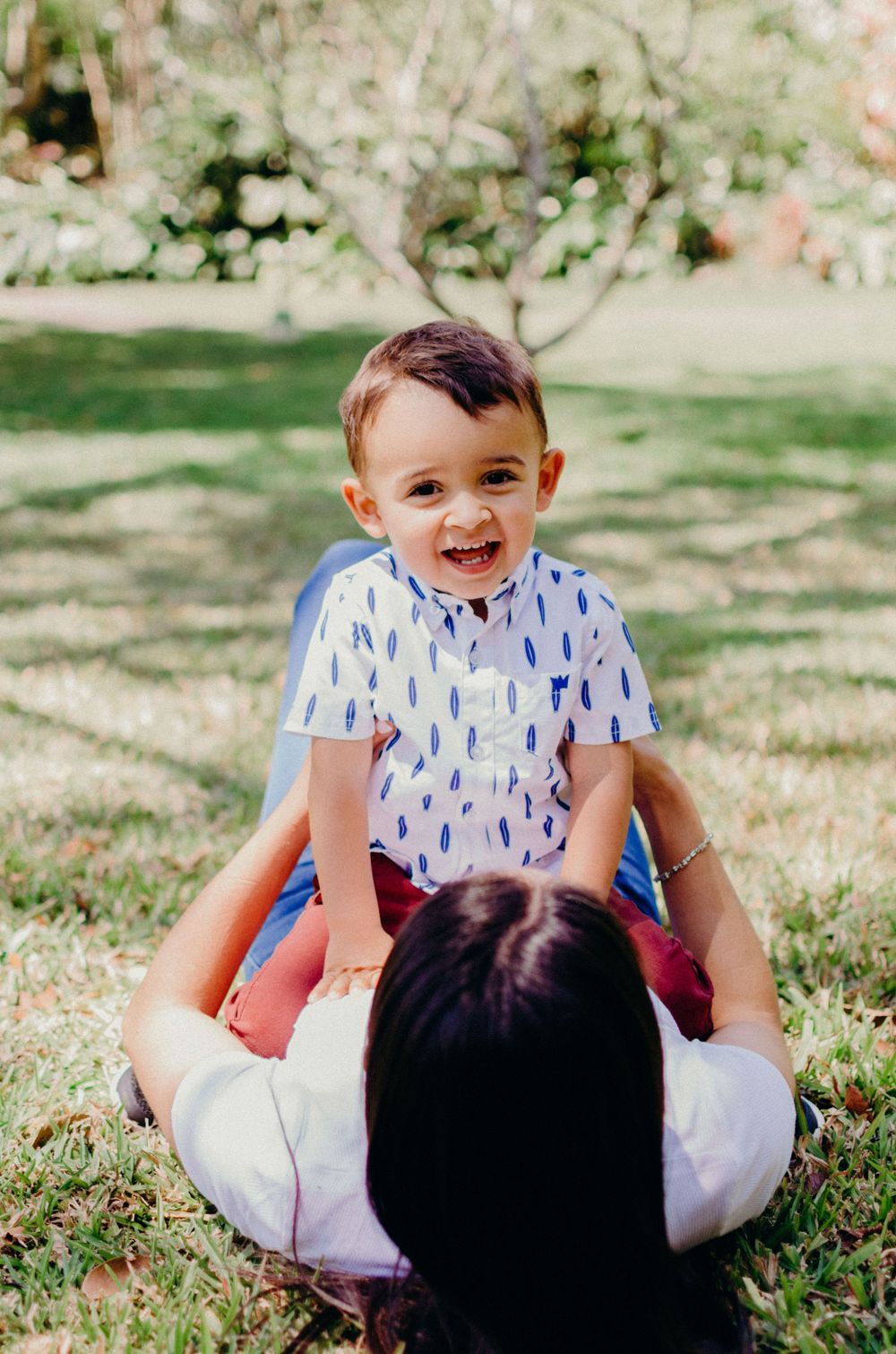 A playful moment of joy captured on grass in dappled sunlight.